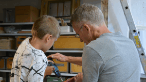 Barn og voksen arbejder sammen om at bygge en fuglekasse