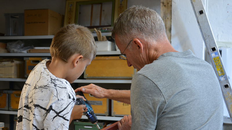 Barn og voksen arbejder sammen om at bygge en fuglekasse